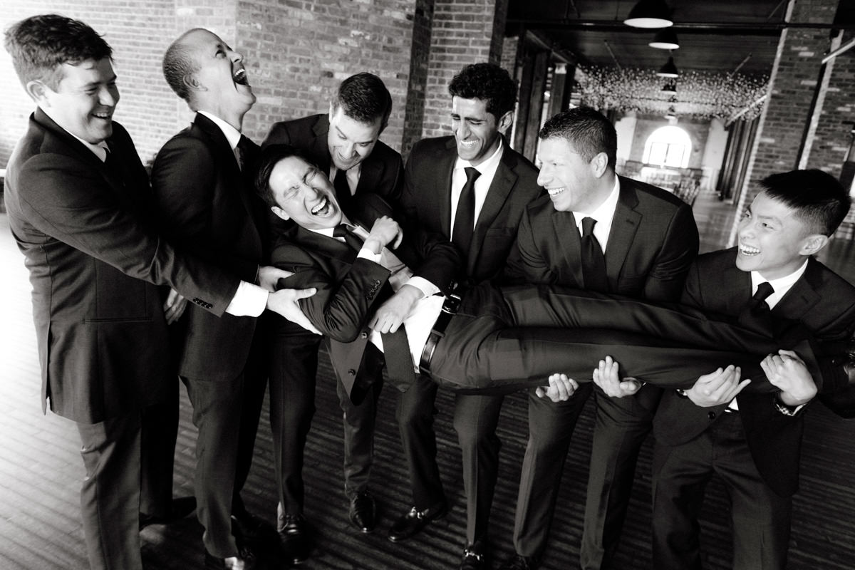 Groomsmen hold up a laughing groom