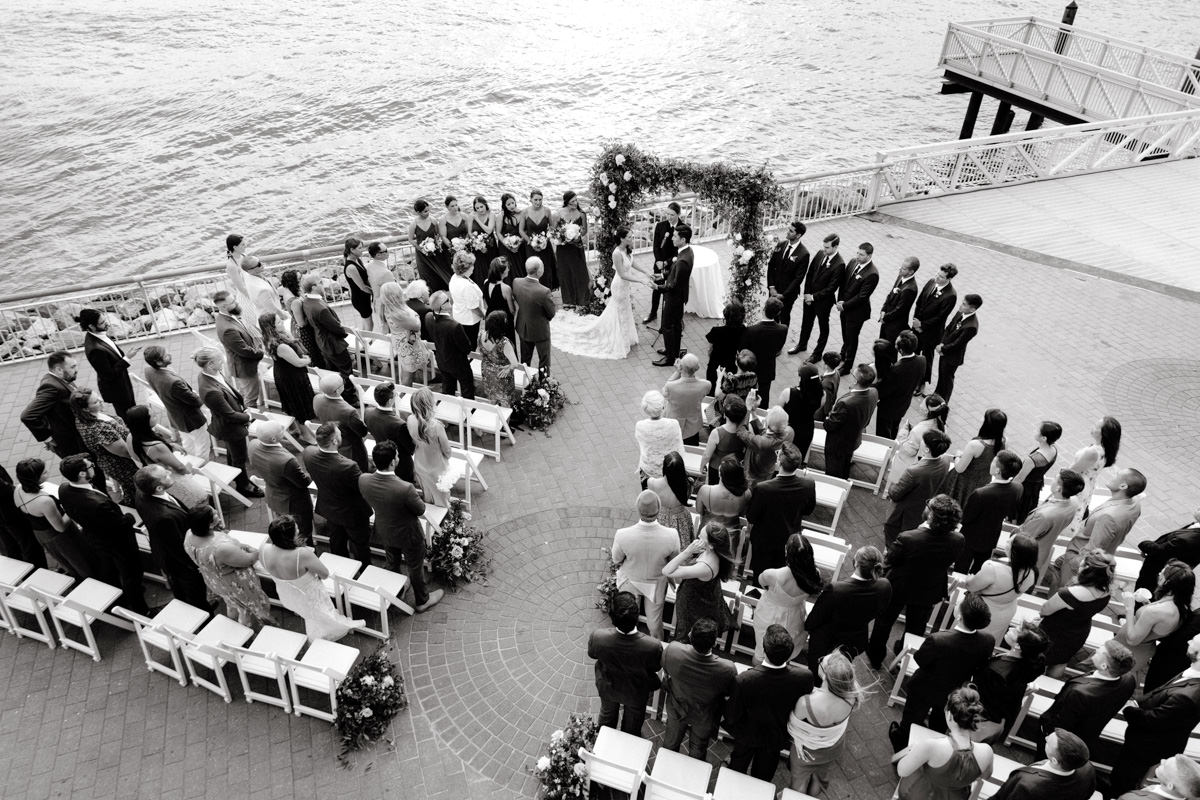 A top view of a beautiful wedding ceremony, above the water, at Liberty Warehouse in Brooklyn, NYC. Image by Jenny Fu Studio