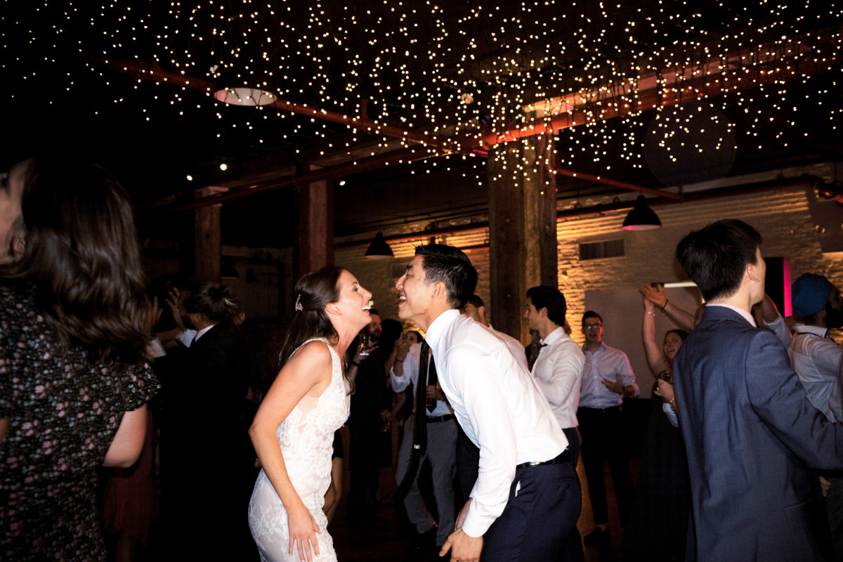 A bride and groom smile at each other on the dance floor
