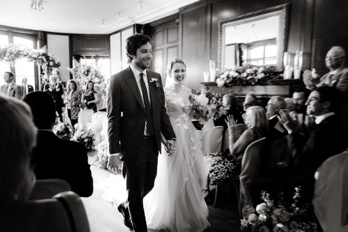 Bride and groom smiling and walking down the aisle as the seated guests clapped.