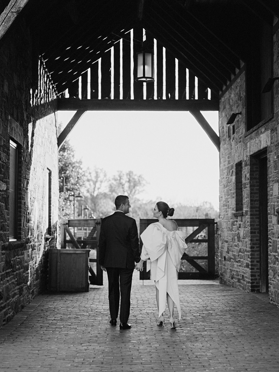 Bride and groom walking, going out of the barn, with their backs facing the camera