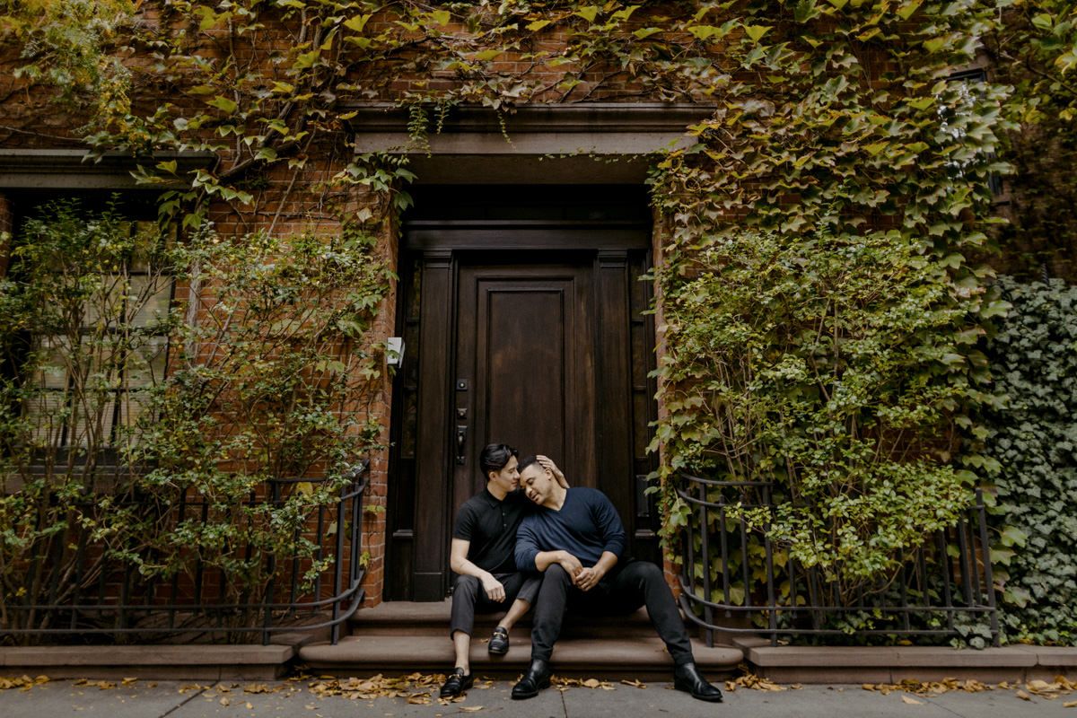 Men couple sitting in front of a house, which is covered with leaves