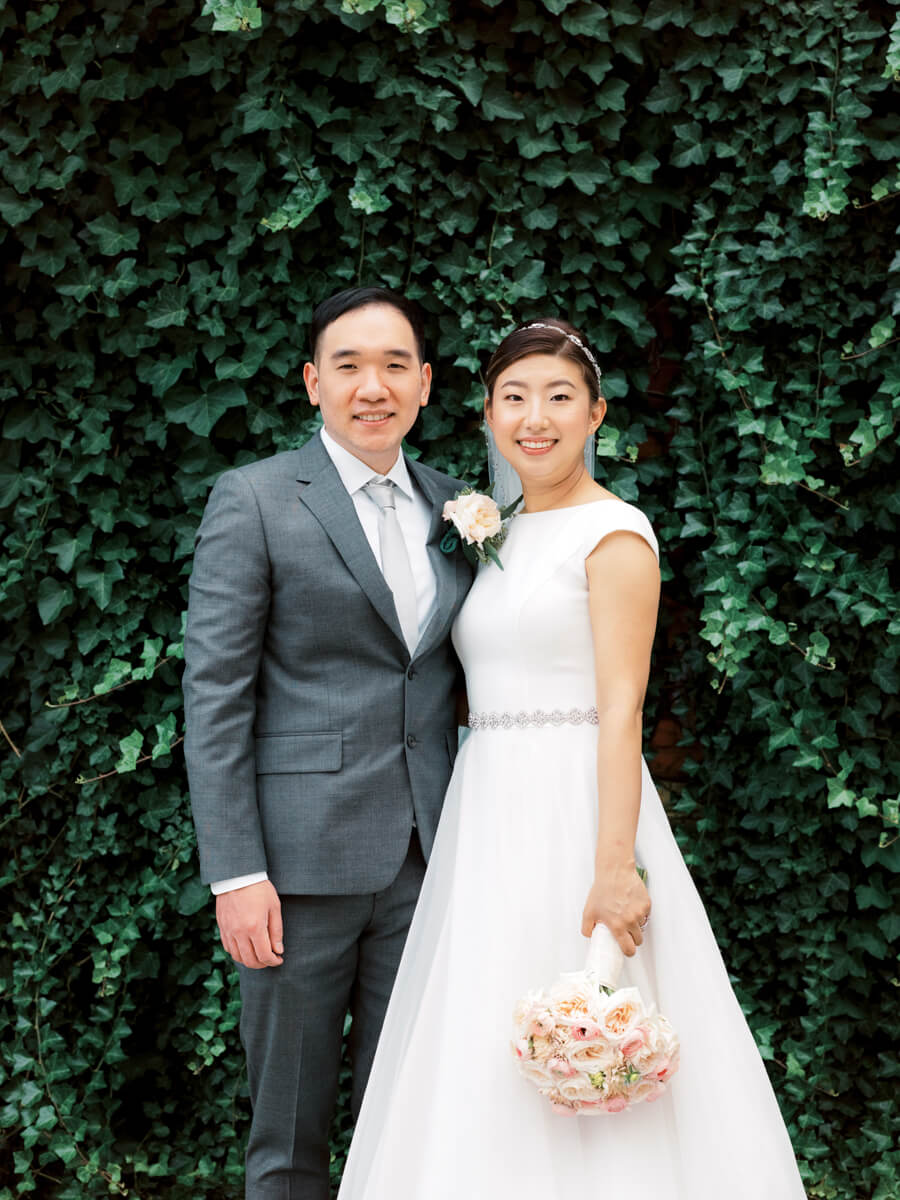 Bride and Groom smiling; green vines on the background
