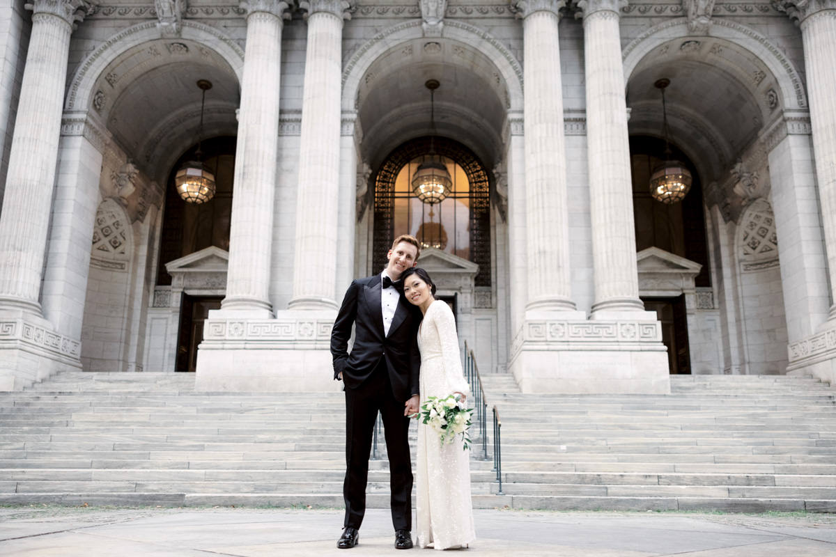 Bride and groom in front of the New York Public Library entrance, with wide staircase and large columns made of marble