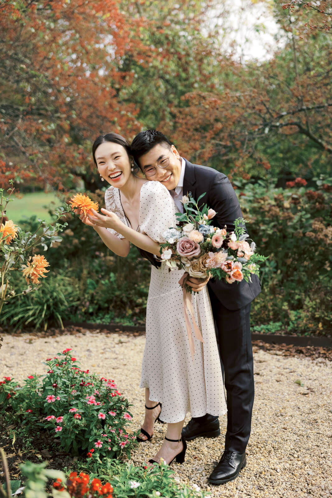 The engaged couple is happily holding beautiful flowers amidst the beautiful fall foliage. Image by Jenny Fu Studio.