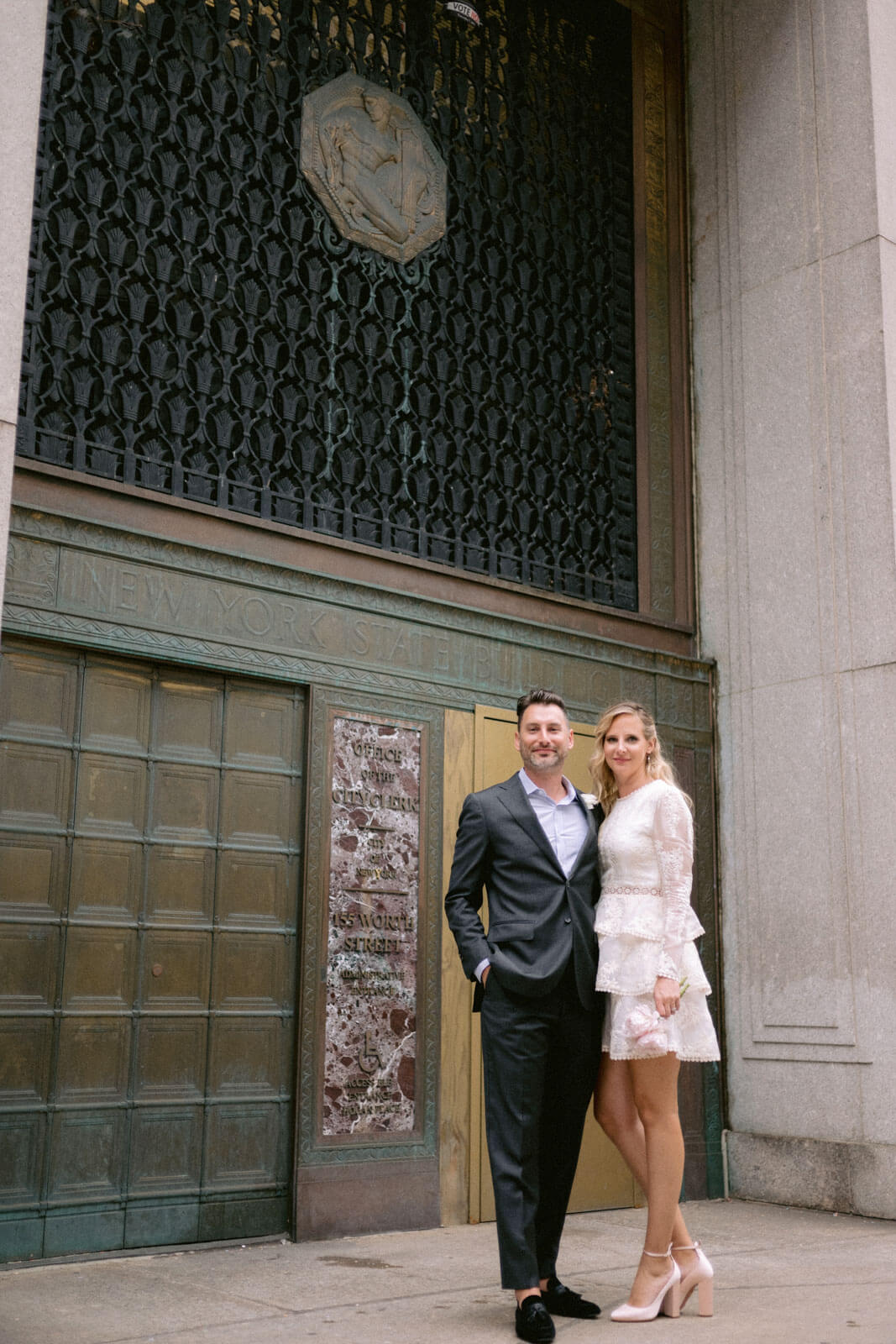 The bride and the groom are standing in front if the New York State Building.