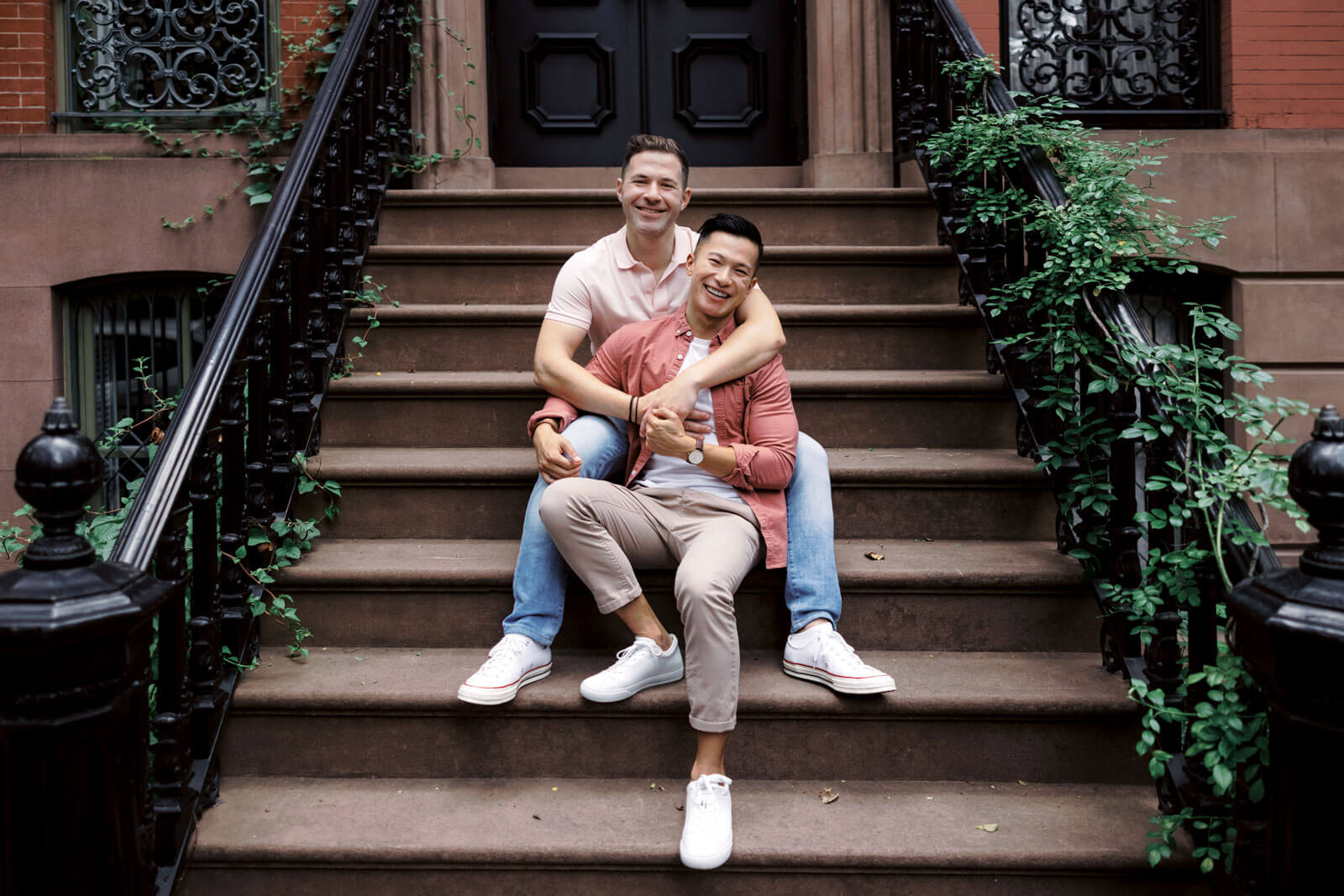 Engagement photos: The engaged couple is sitting on a staircase outside of a house at West Village Madison Square Park, NYC.