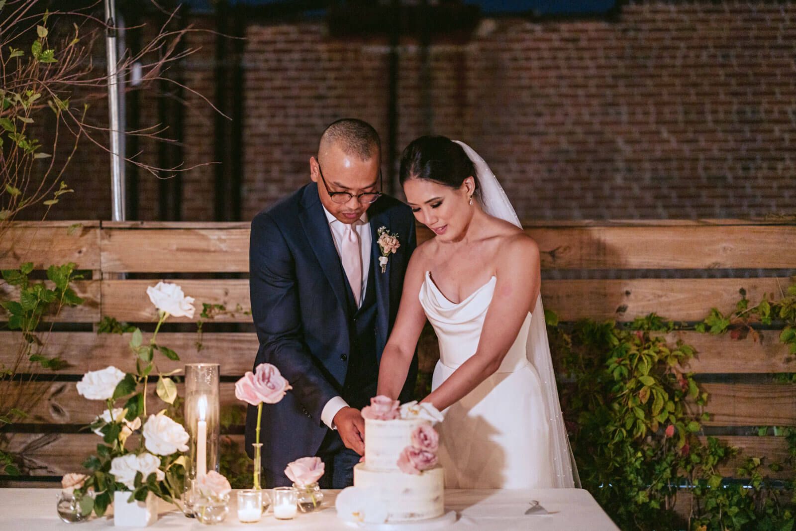 The newlyweds are cutting a slice of their small cake in a New York City elopement. Image  by Jenny Fu Studio