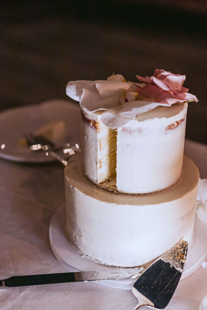 A small, white, two-tiered, naked wedding cake already sliced by the newlyweds in New York City. Image by Jenny Fu Studio
