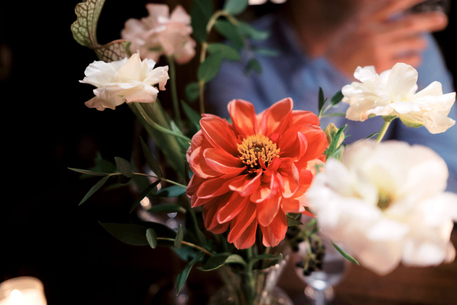 A flower in vibrant red-orange color with white flowers around it. Holiday New York City Hall elopement Image by Jenny Fu Studio