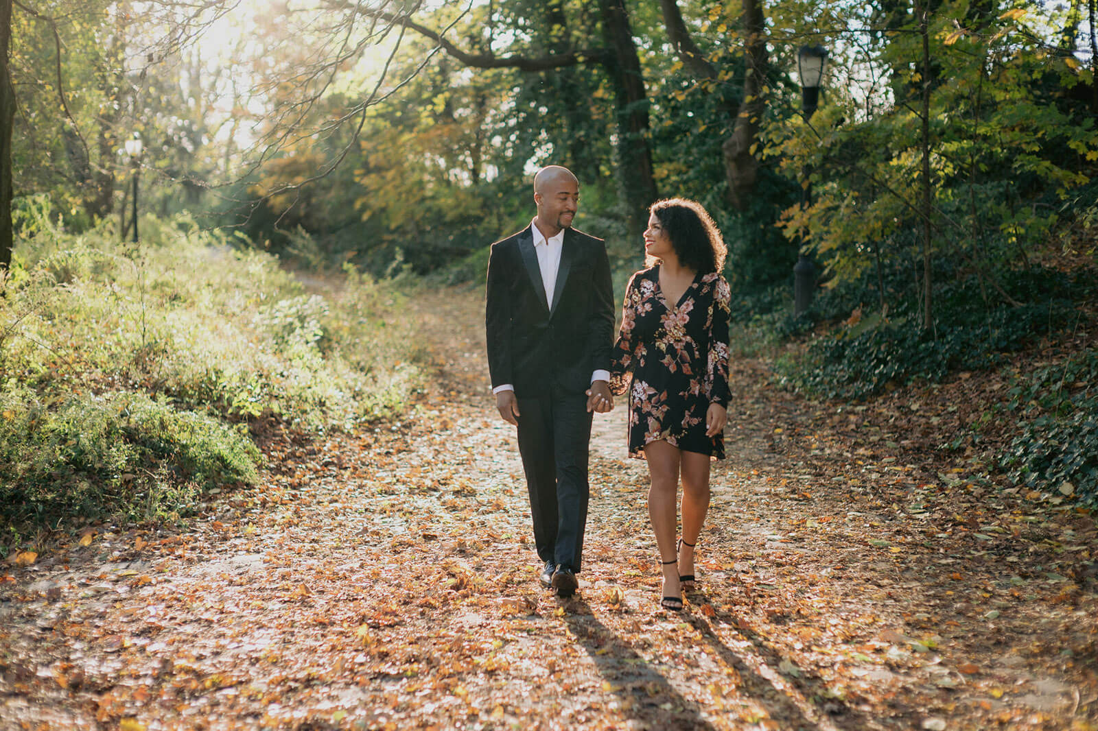 The engaged couple is happily walking in a park. NYC Christmas Engagement Photos by Jenny Fu Studio  
