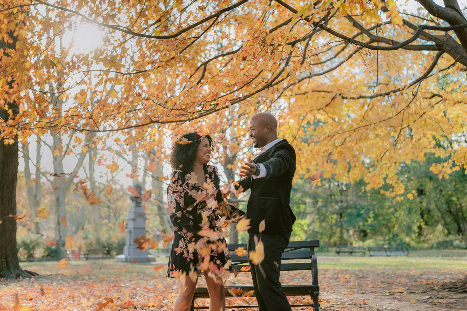 The engaged couple is laughing together under a tree in a park in Brooklyn. NYC Christmas Engagement Photos by Jenny Fu Studio  