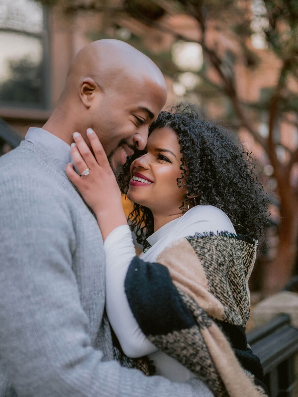 The woman is happily staring at her fiance in Brooklyn. NYC Christmas Engagement Photos by Jenny Fu Studio