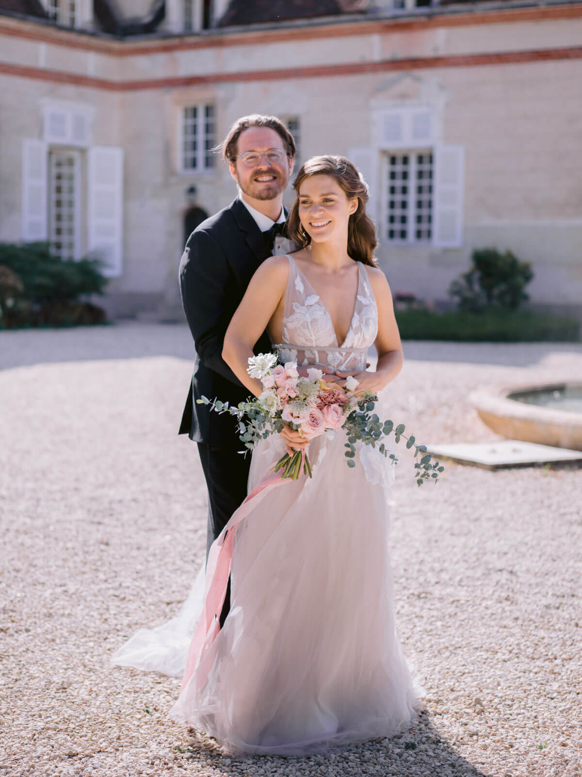 The bride and groom are standing in front of a chateau in France. Image by Destination Wedding Photographer Jenny Fu