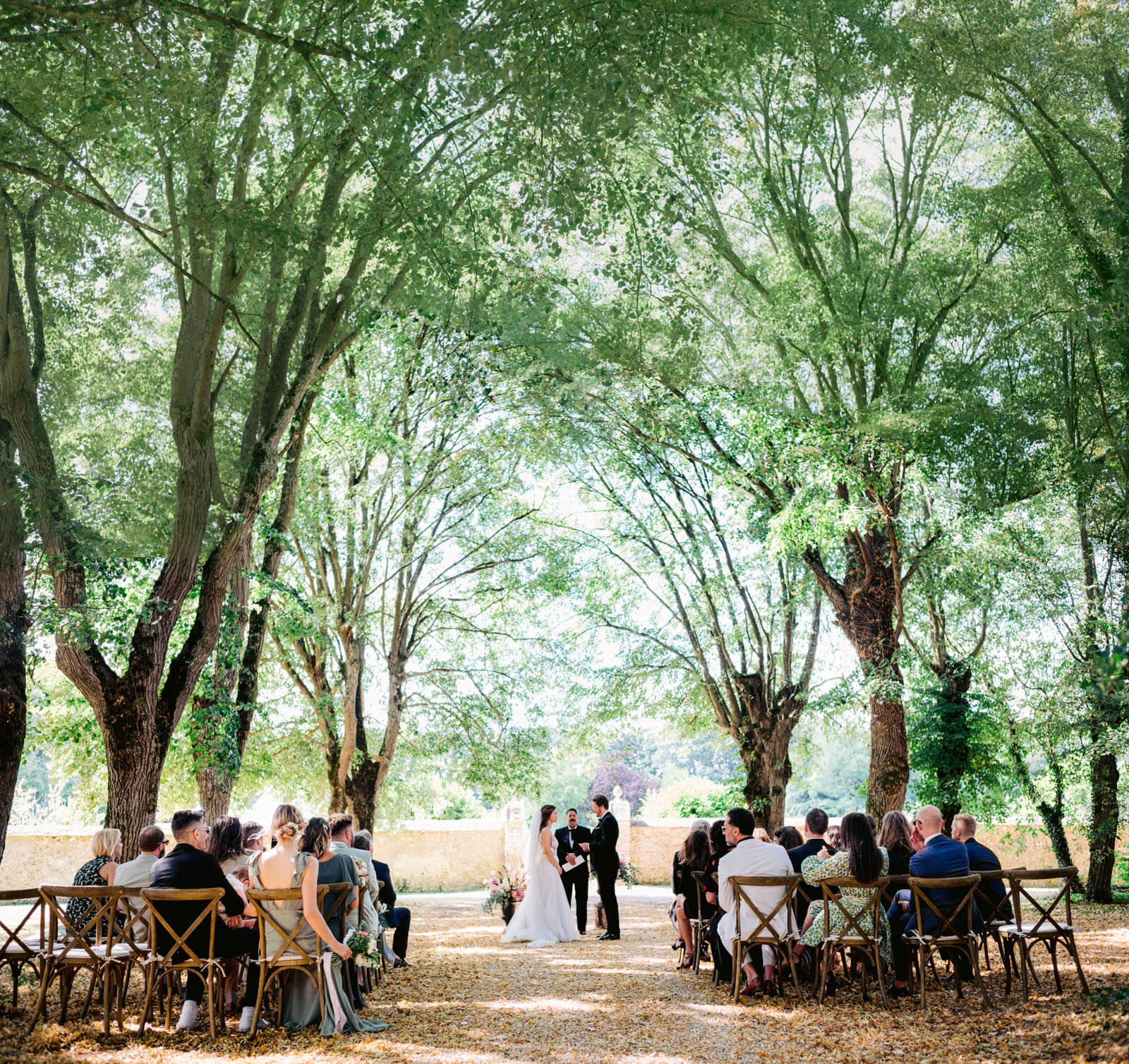 A beautiful, rustic, wedding ceremony amidst tall trees. Outdoor wedding destination image by Jenny Fu Studio