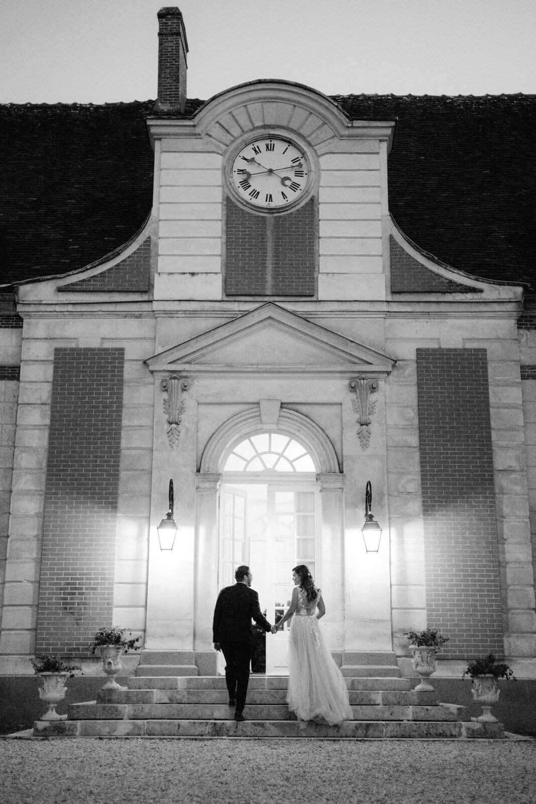 Black and white photo of the bride and groom going inside the chateau after the wedding in France. Image by Jenny Fu Studio