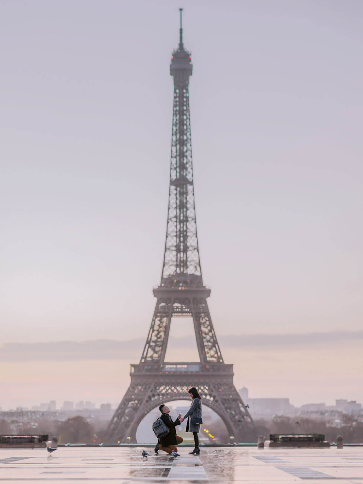 The man is on bended knees, proposing to his fiancee in front of the Eiffel Tower, Paris, France. Image by Jenny Fu Studio