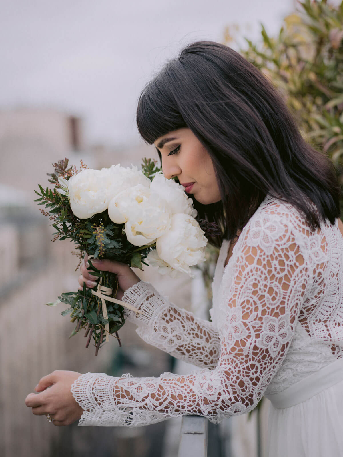 The bride is smelling her flower bouquet in Paris, France. New Year's Destination wedding image by Jenny Fu Studio