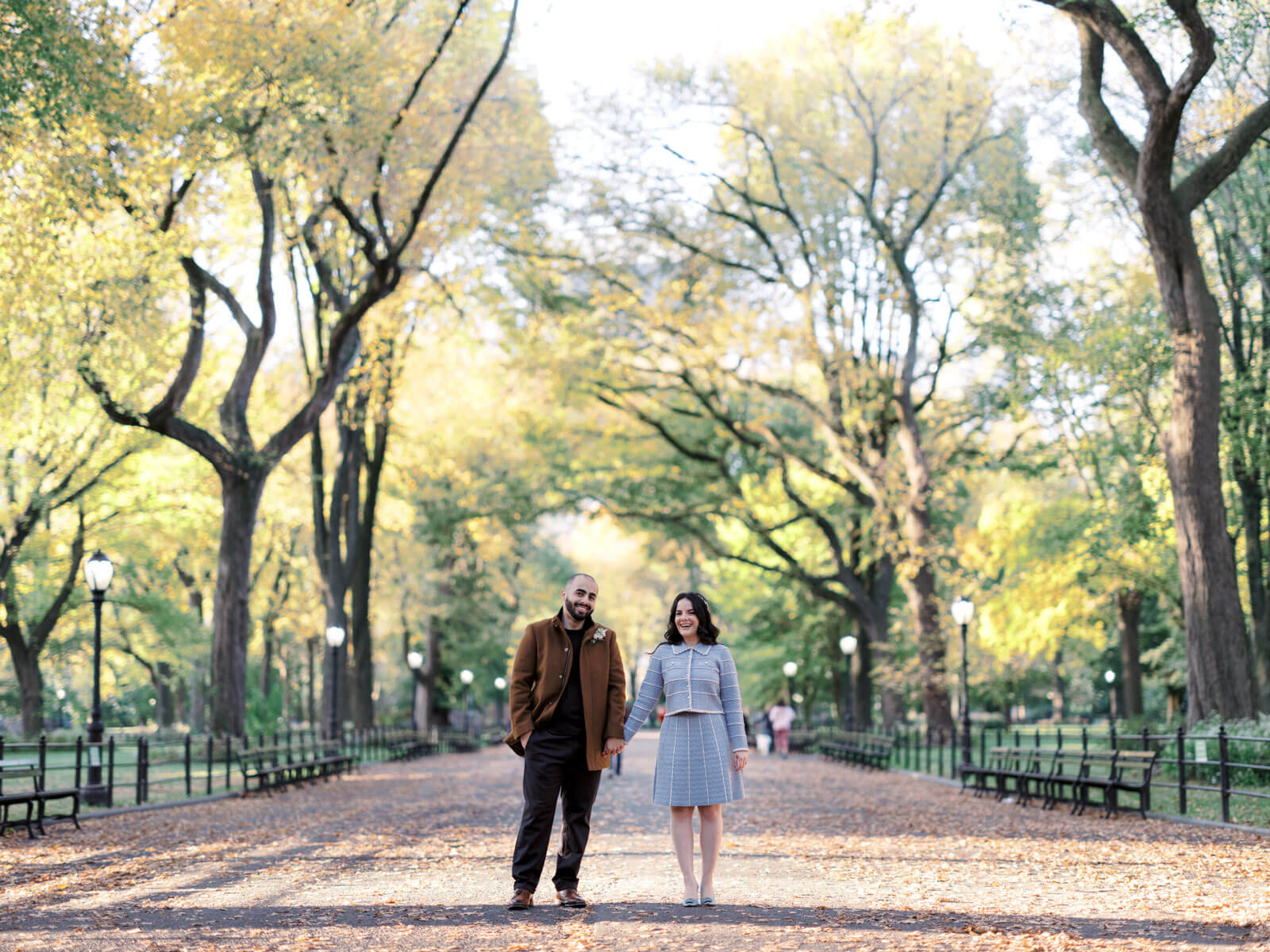The engaged couple are standing in the middle of a park in NYC. Engagement photo image by Jenny Fu Studio