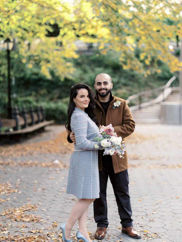 The engaged couple is standing in the middle of a park. Engagement photo location at a NYC park.