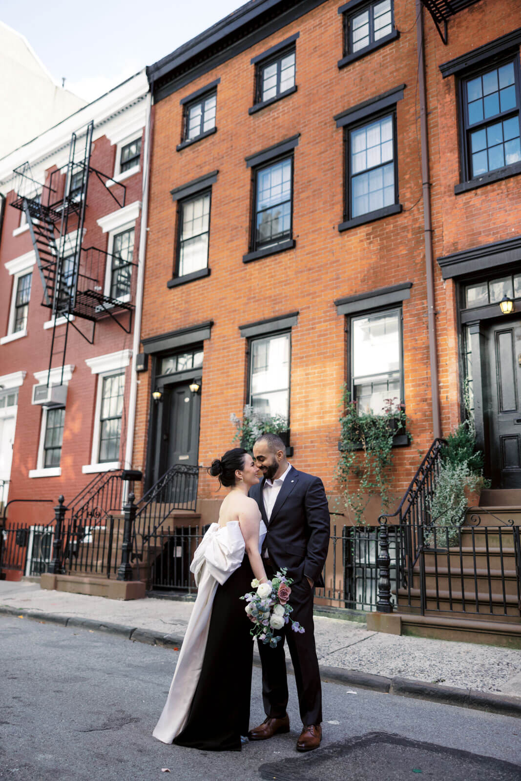 The engaged couple is standing close in front of a townhouse. Engagement photo location at West Village, NYC.