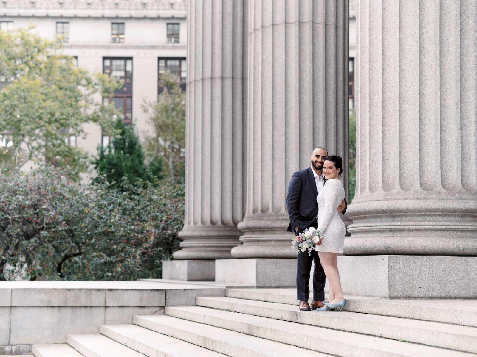The bride and groom are standing outside NYC City Hall. Elopement image by Jenny Fu Studio