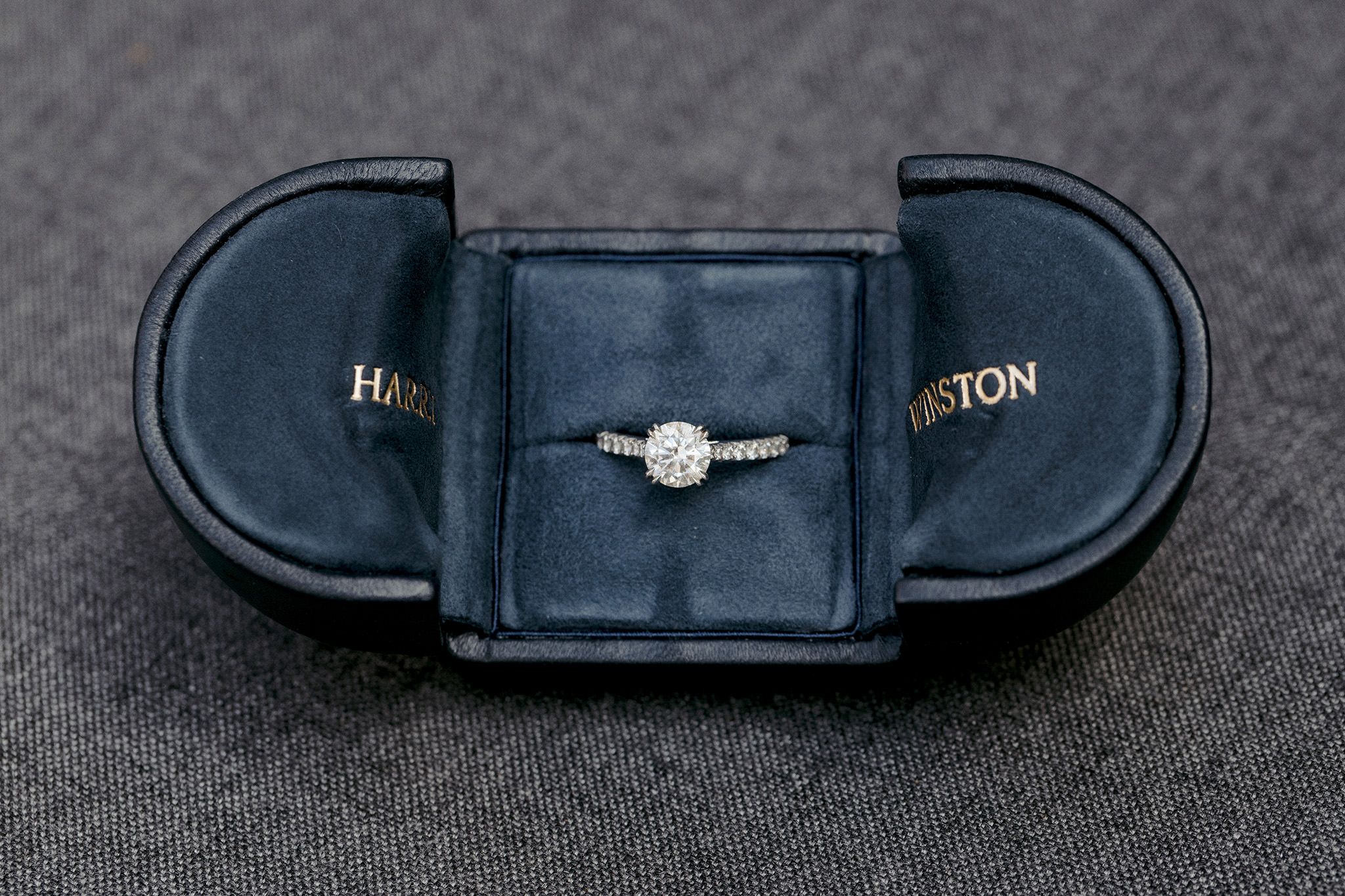 A diamond engagement ring inside a navy blue box. Image by Jenny Fu Studio