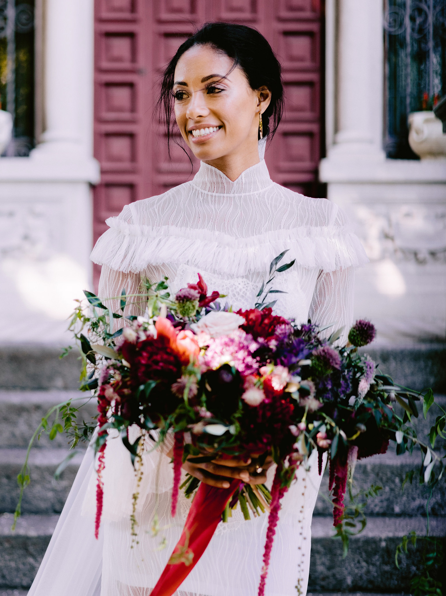 The bride is holding a beautiful bouquet with a mix of red, maroon, purple, and white flowers. Image by Jenny Fu Studio