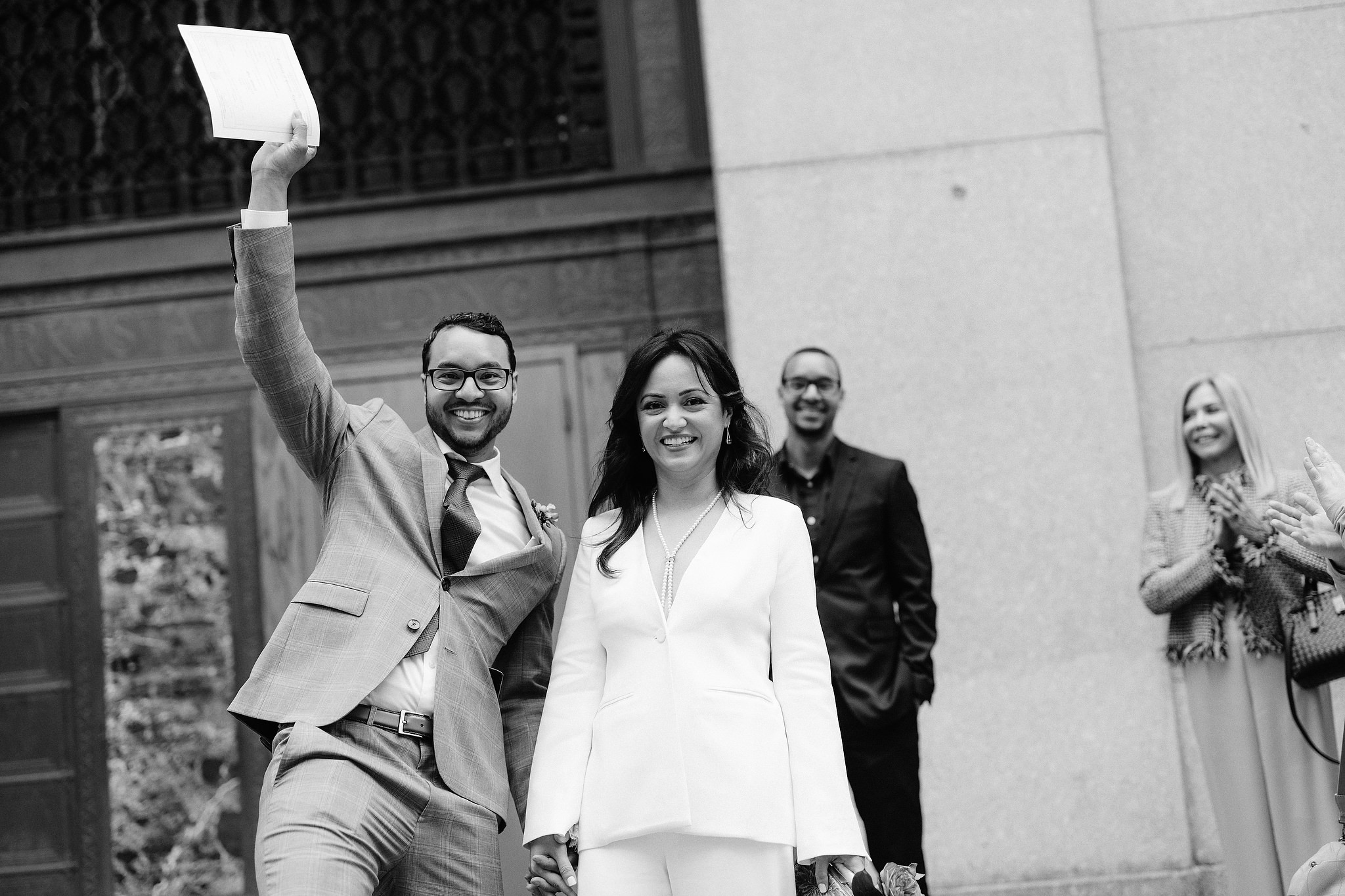The bride and groom happily went out of the exit door of NYC City Hall after their wedding ceremony. Elopement image by Jenny Fu Studio