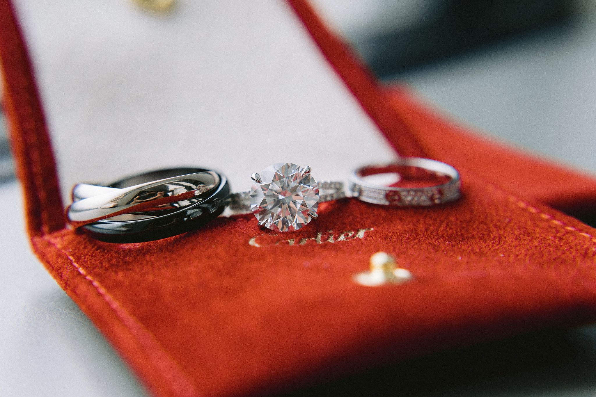 The diamond engagement ring and wedding bands are placed on top of a cartier velvet pouch. Image by Jenny Fu Studio