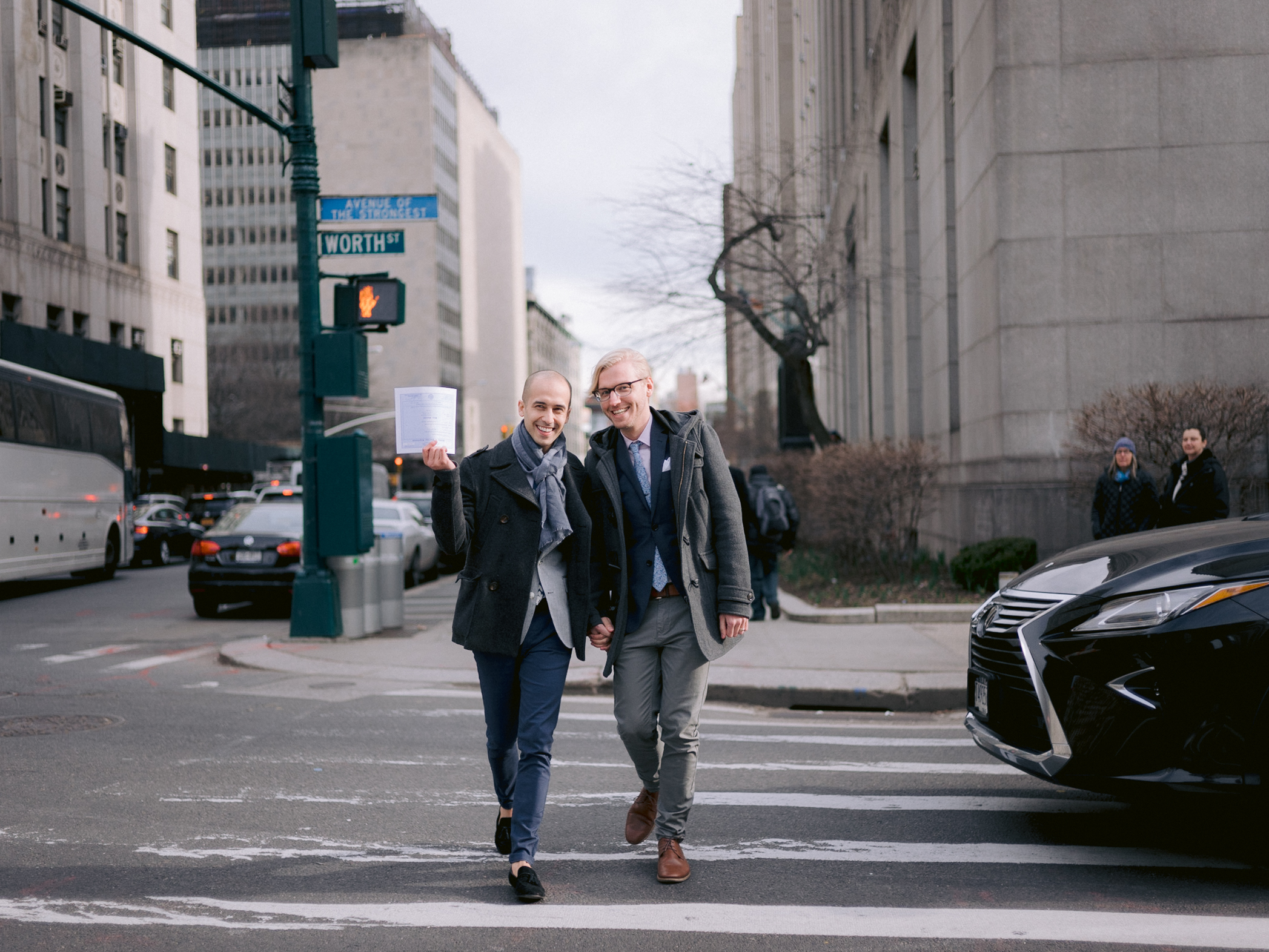The two grooms are crossing Worth Street after their wedding ceremony at NYC City Hall. Elopement image by Jenny Fu Studio