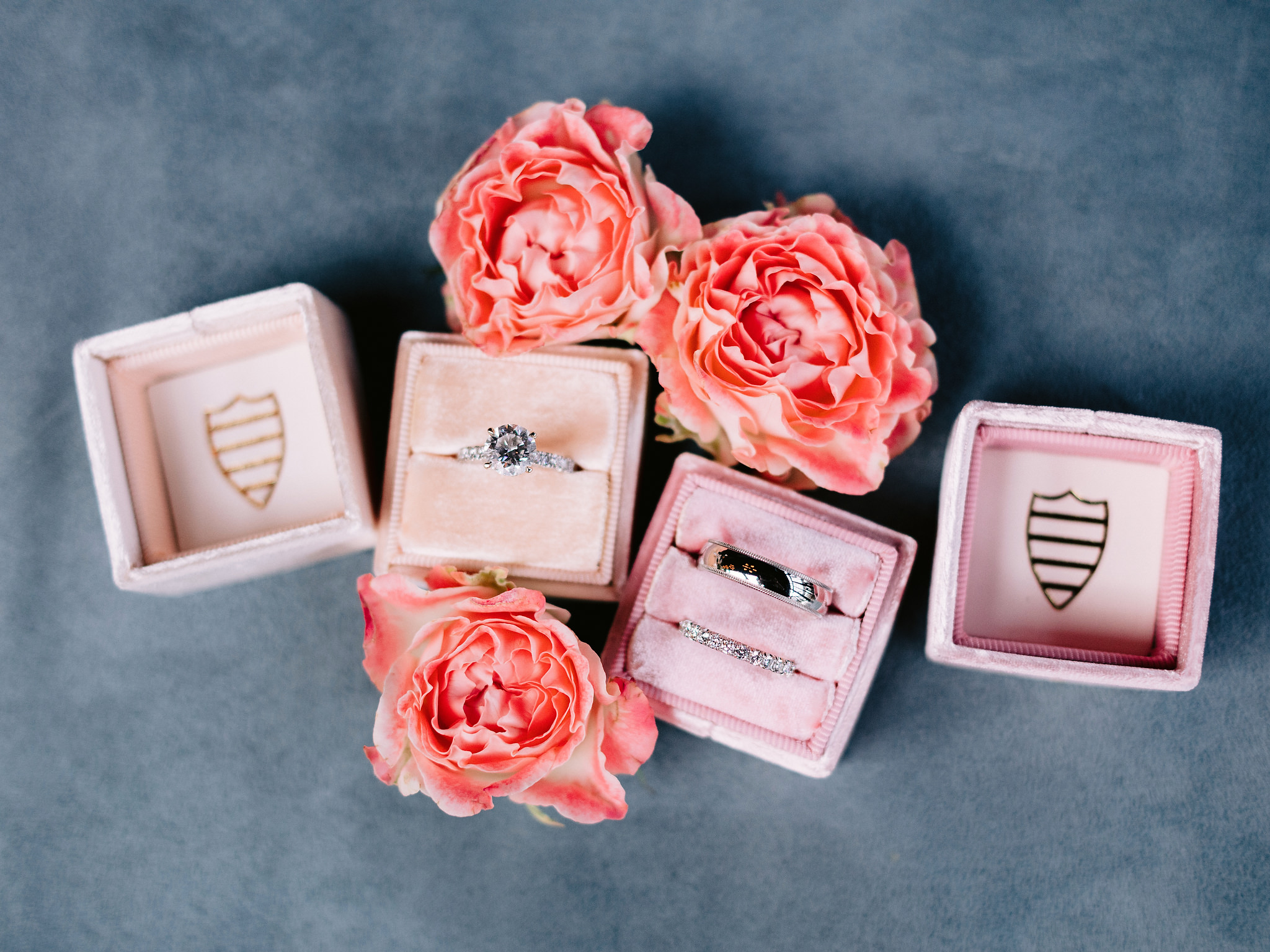 The diamond engagement ring and wedding bands are placed in pink boxes with pretty pink flowers on the sides. Image by Jenny Fu Studio