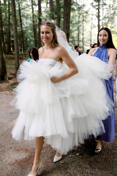 The bride is walking, with a bridesmaid holding her dress at the back