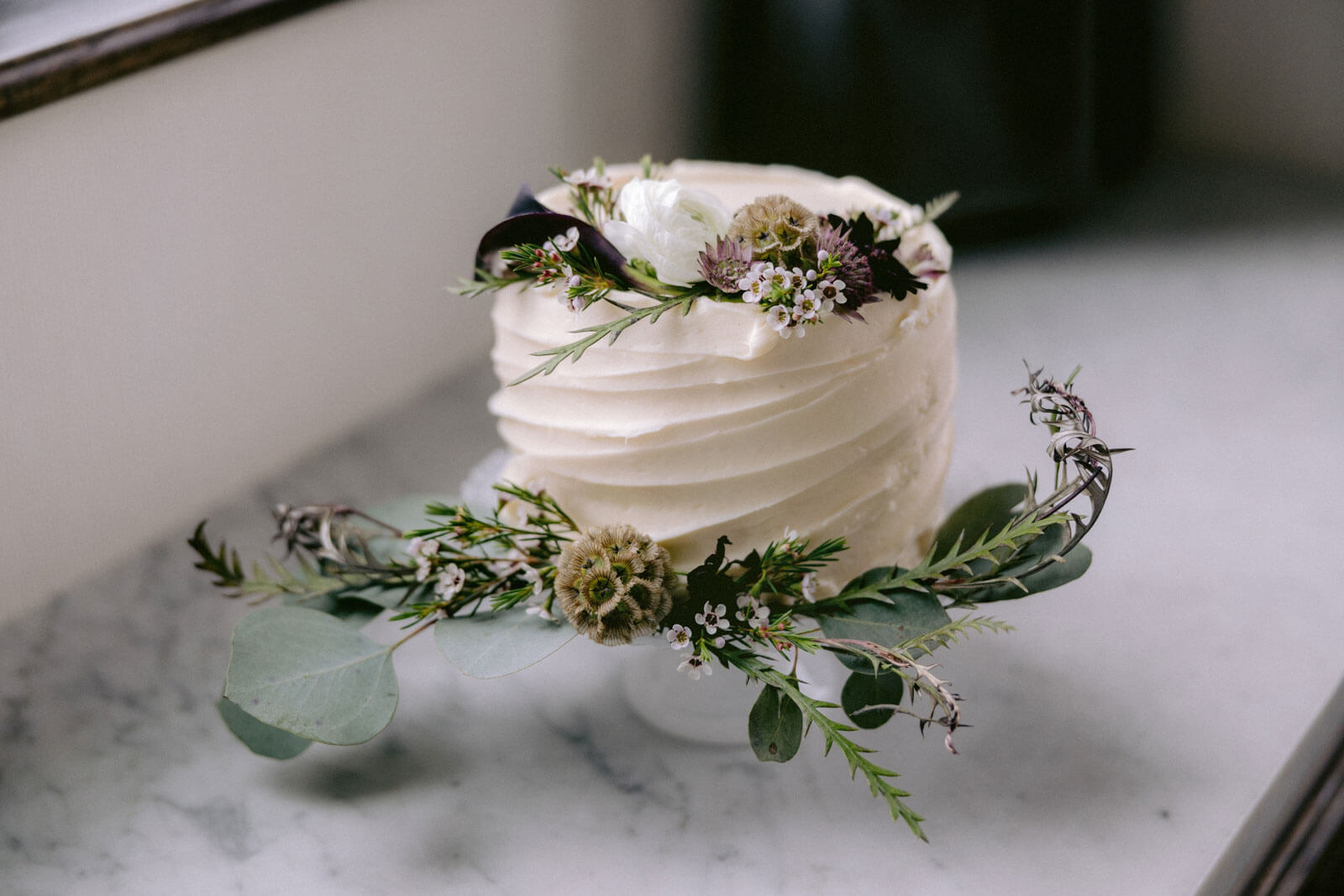 A small, pretty white wedding cake with flower accent in NYC. Image by Jenny Fu Studio