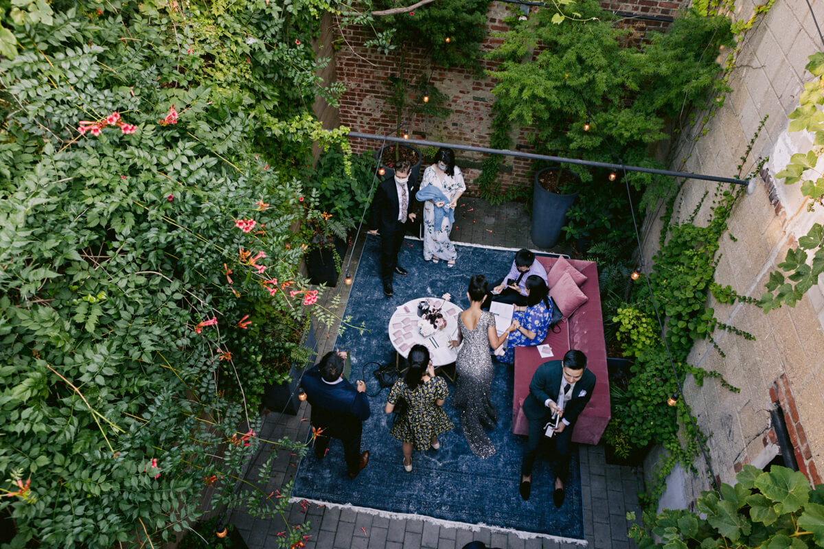 Top view of a few wedding guests chatting on a lounge area with many green plants in New York. Image by Jenny Fu Studio