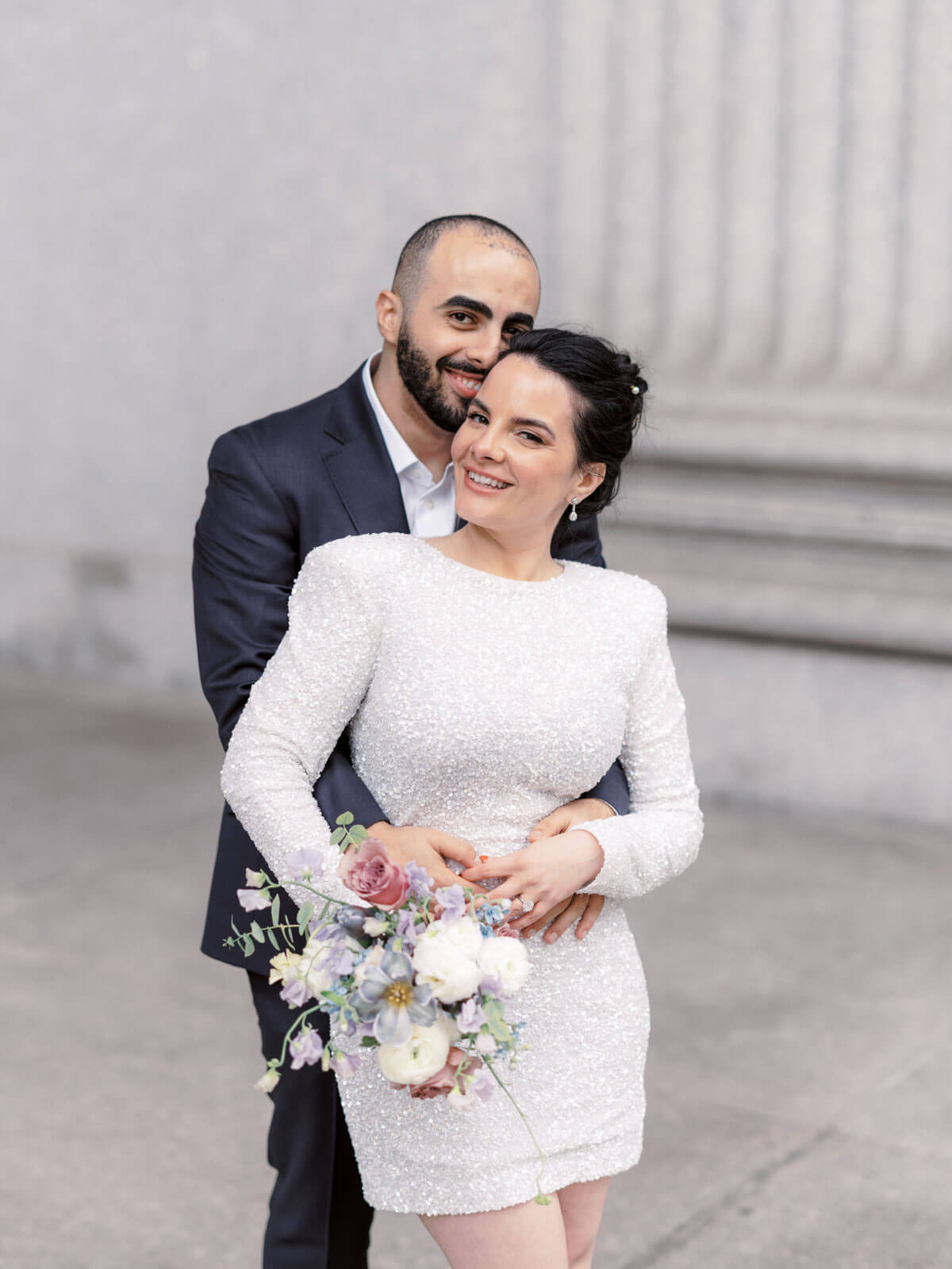 The groom is lovingly hugging the bride from the back. NY City Hall Elopement image by Jenny Fu Studio