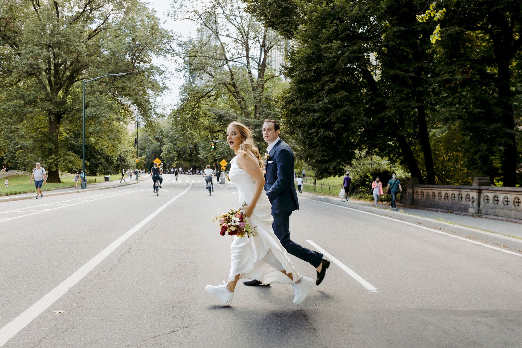 The bride and groom are crossing the street of New York City.