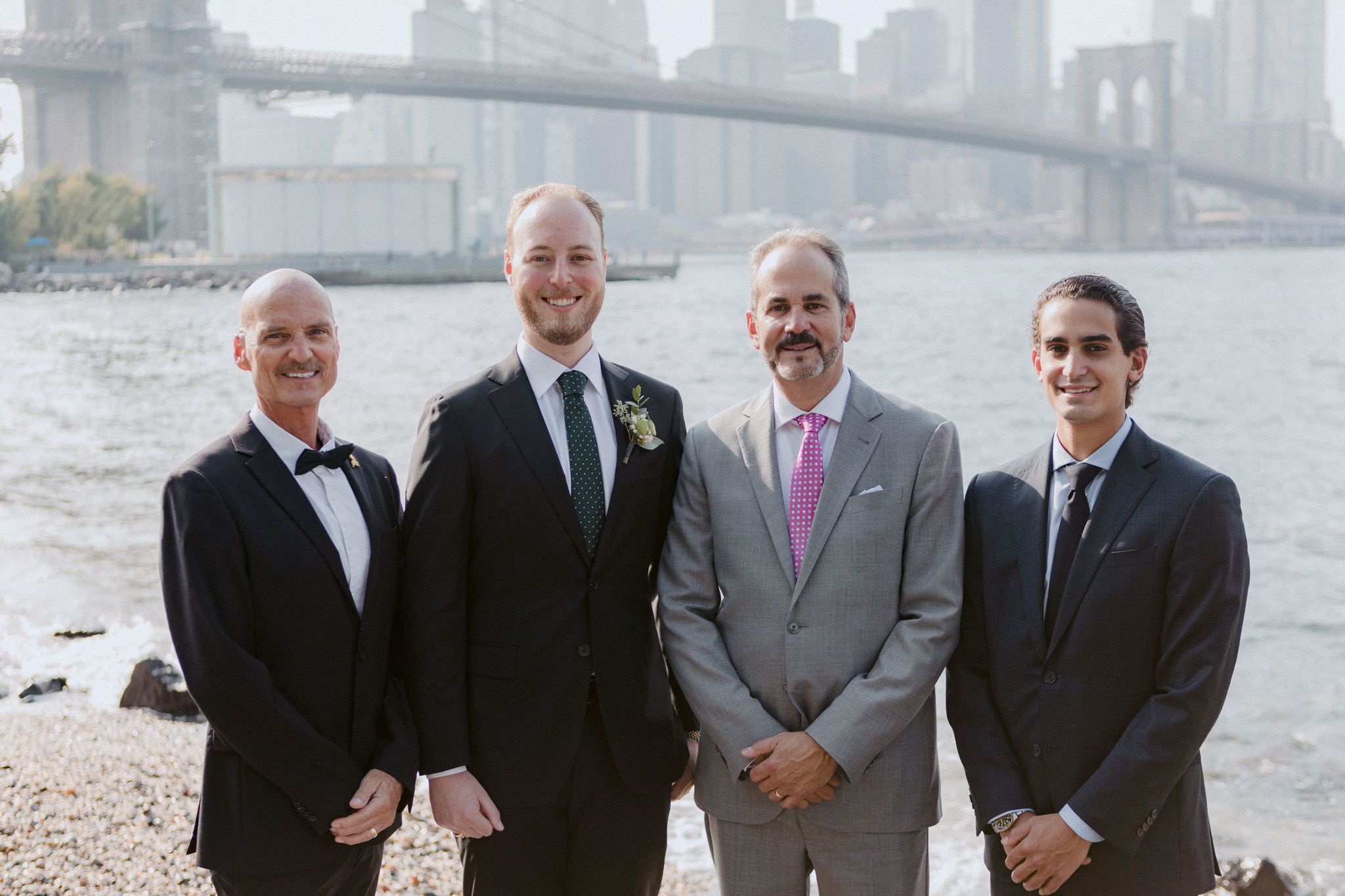 The groom is standing beside his father and groomsmen in NYC.
