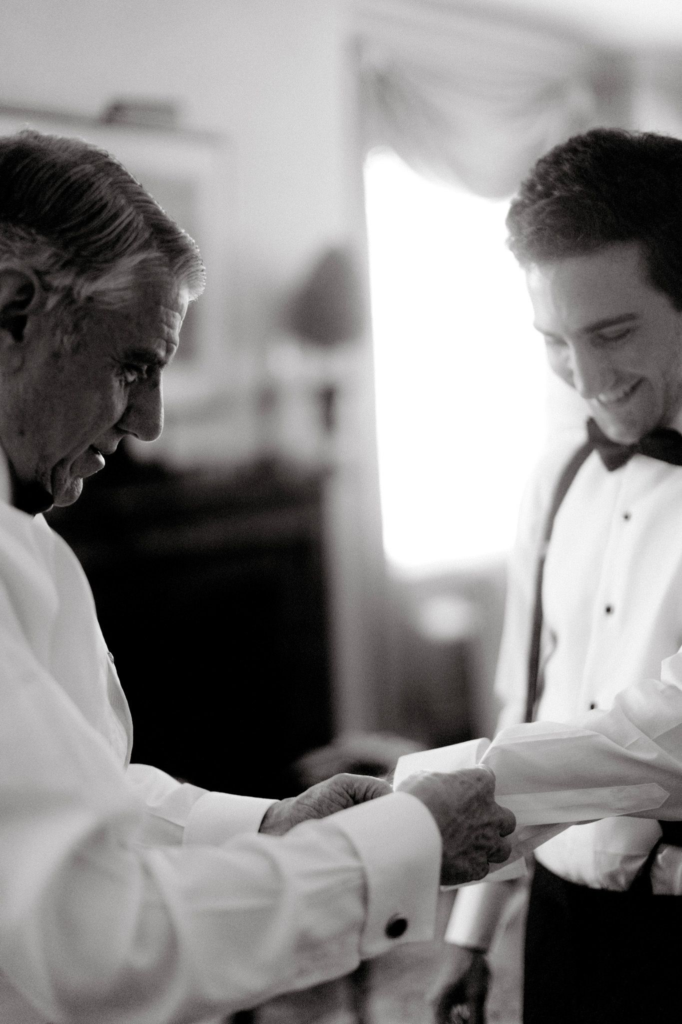 The father of the groom is buttoning his son's cuffs. Image by Jenny Fu Studio NYC