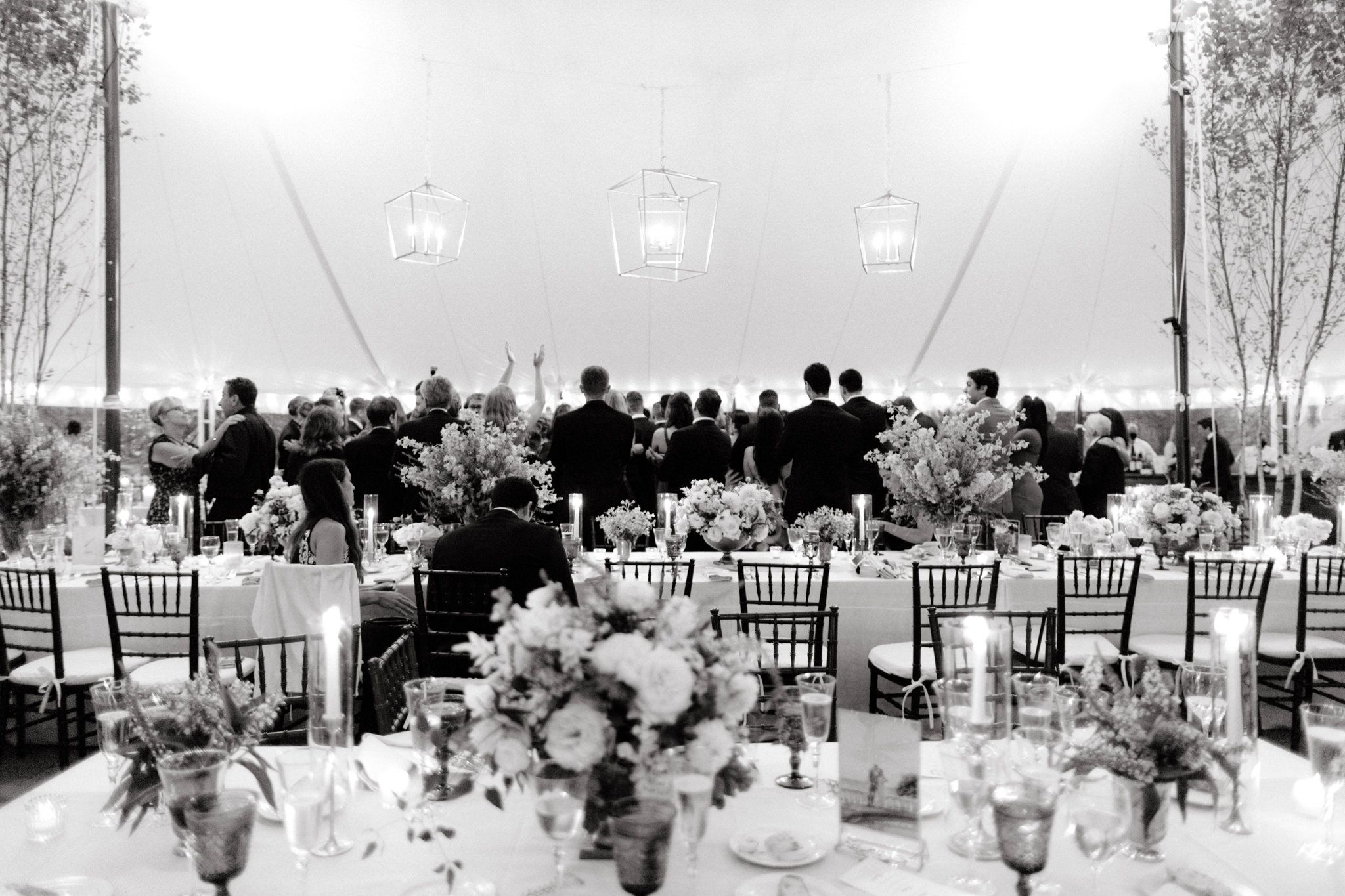 Black and white photo of the wedding guests dancing inside wedding reception venue. Destination image by Jenny Fu Studio 