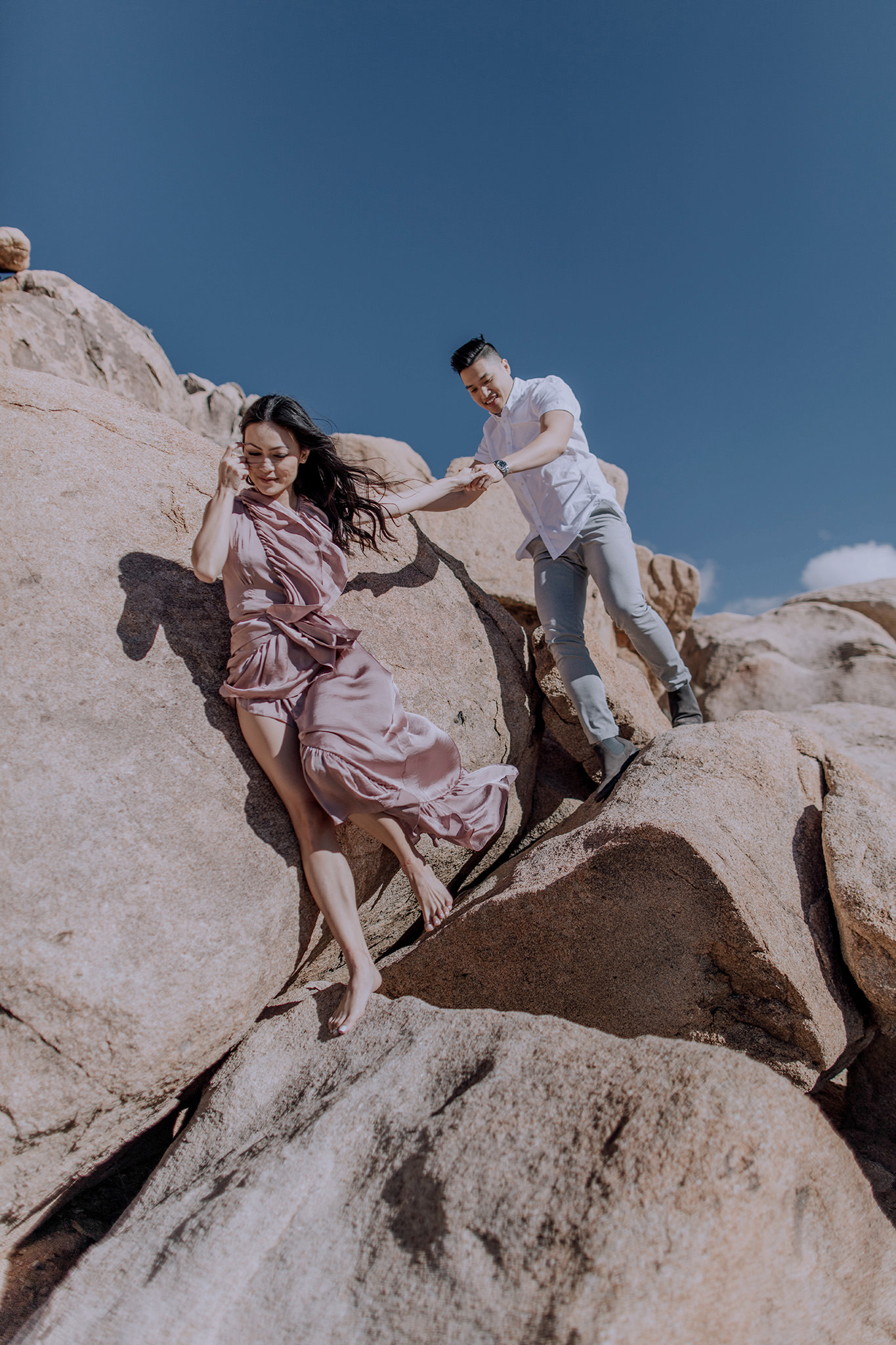 The engaged couple are walking down the big rocks. Engagement image by Jenny Fu Studio