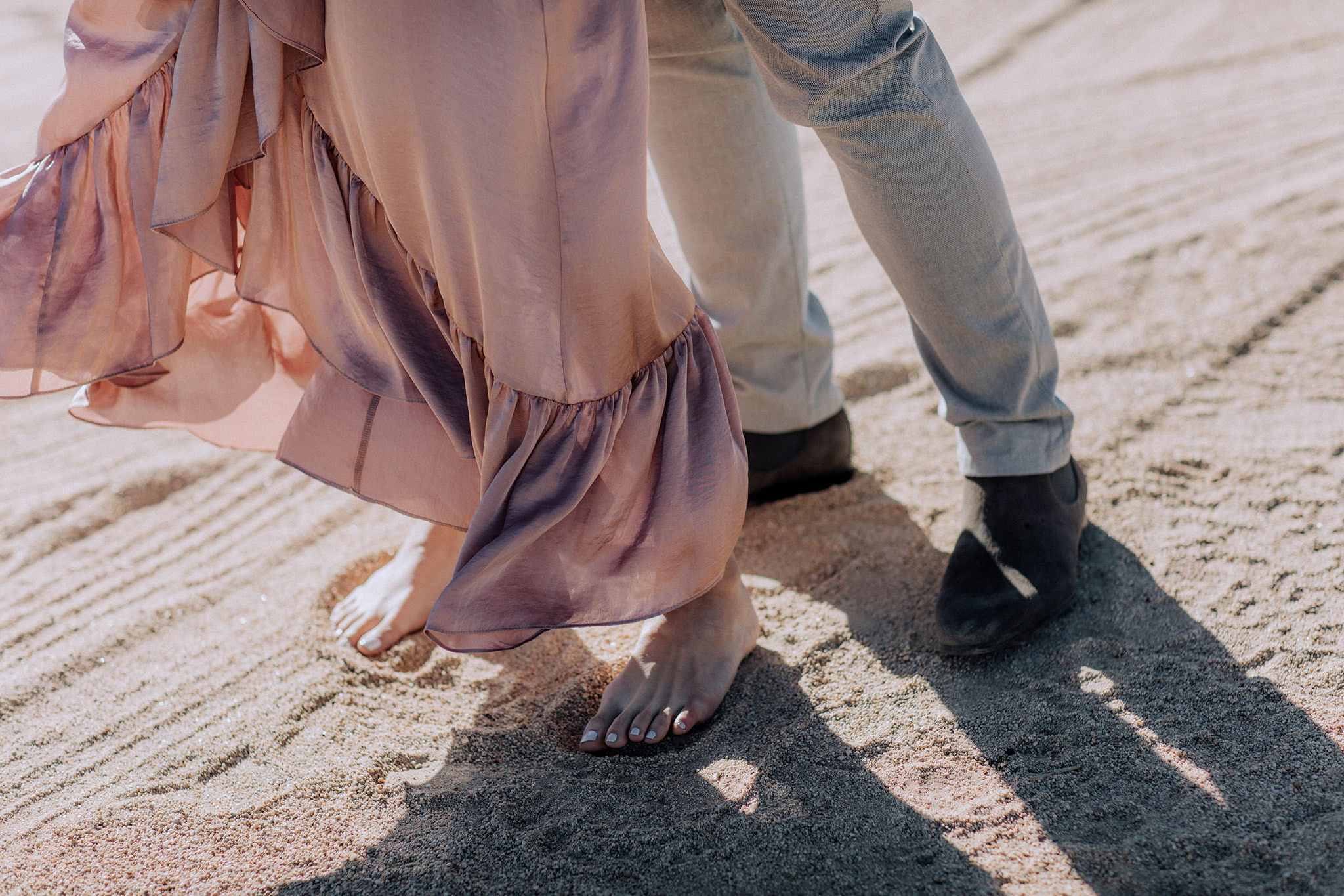 The engaged couple's feet on the sand. Engagement image by Jenny Fu Studio