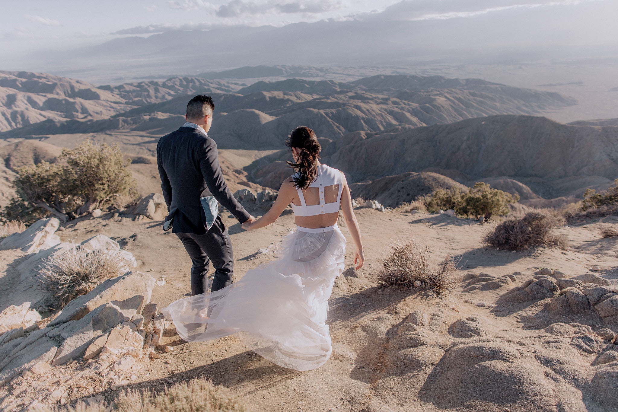 The engaged couple are walking in the mountains. Spring engagement session outfit image by Jenny Fu Studio