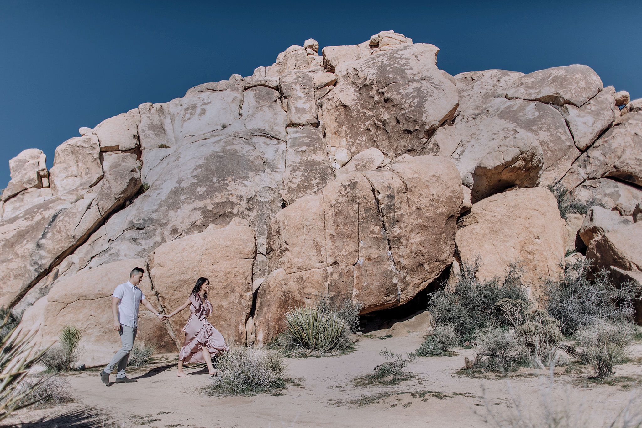 The engaged couple are walking in the mountains, with large rocks in the background. Engagement image by Jenny Fu Studio