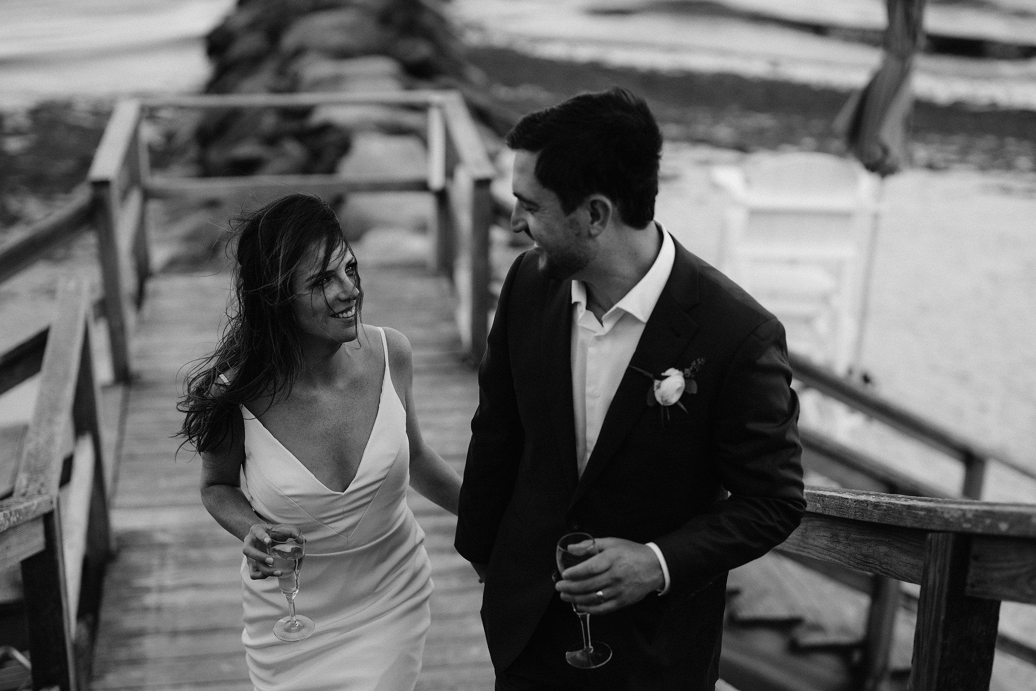 The bride and groom are happily walking on the dock in the seashore. Wianno Club, Cape Cod, Osterville, MA. Beach wedding venue image by Jenny Fu Studio