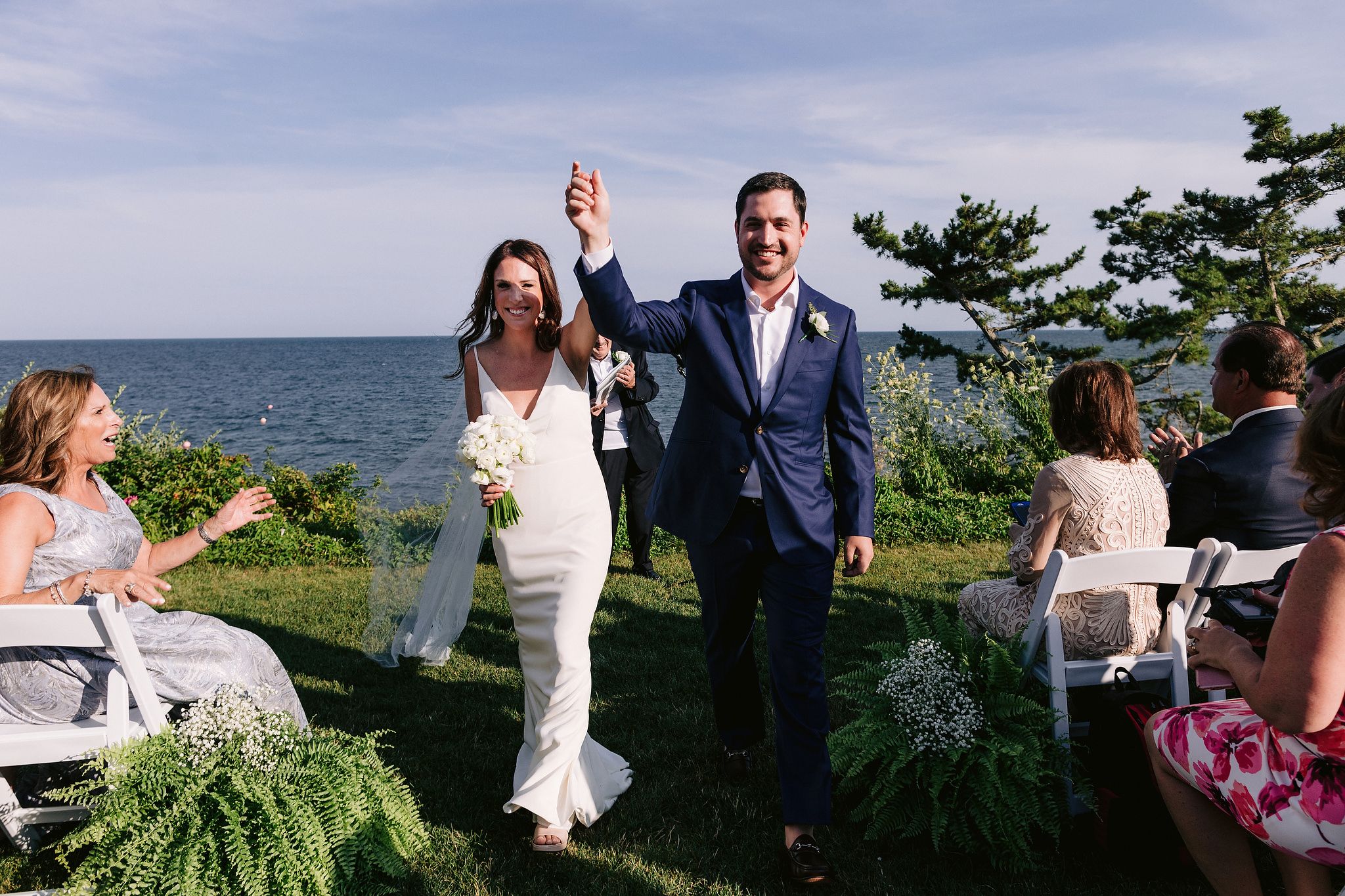 The bride and groom are happily walking away in the aisle after saying their vows. Wianno Club, Cape Cod, Osterville, MA. Beach wedding venue image by Jenny Fu Studio