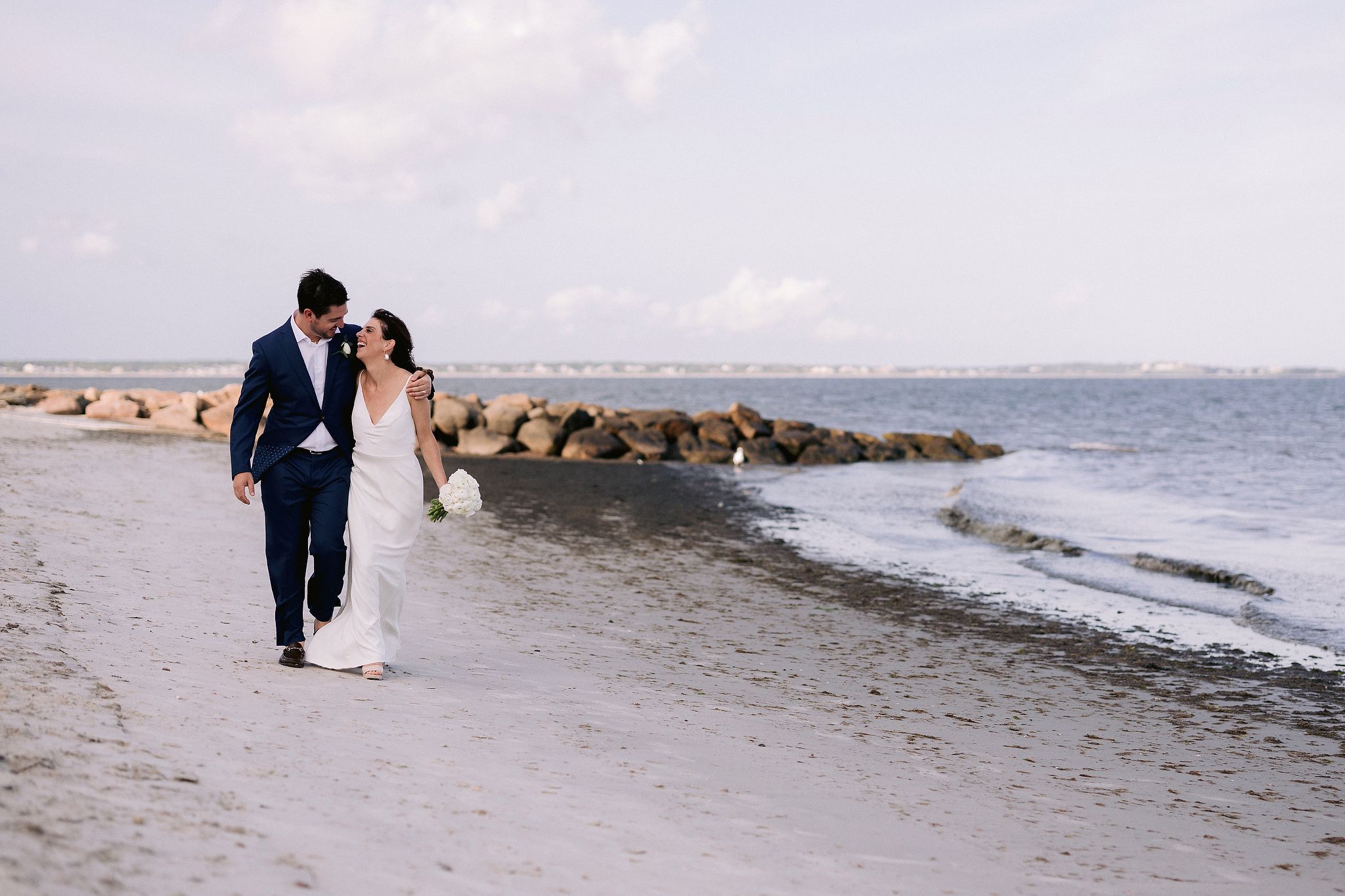 The couple are walking happily on the seashore. Wianno Club, Cape Cod, Osterville, MA Beach wedding venue image by Jenny Fu Studio