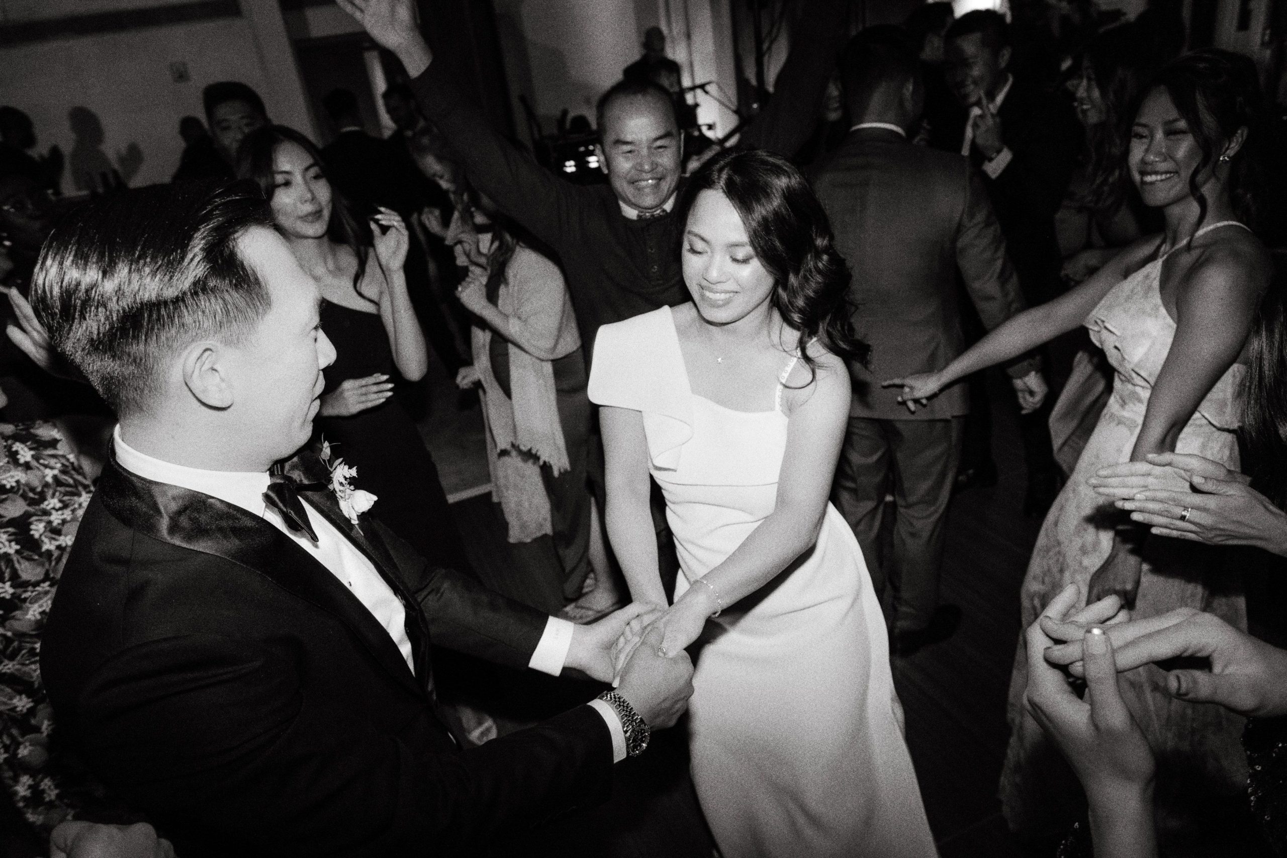 Black and white editorial image of the bride and groom dancing with guests. Hiring a wedding planner image by Jenny Fu Studio