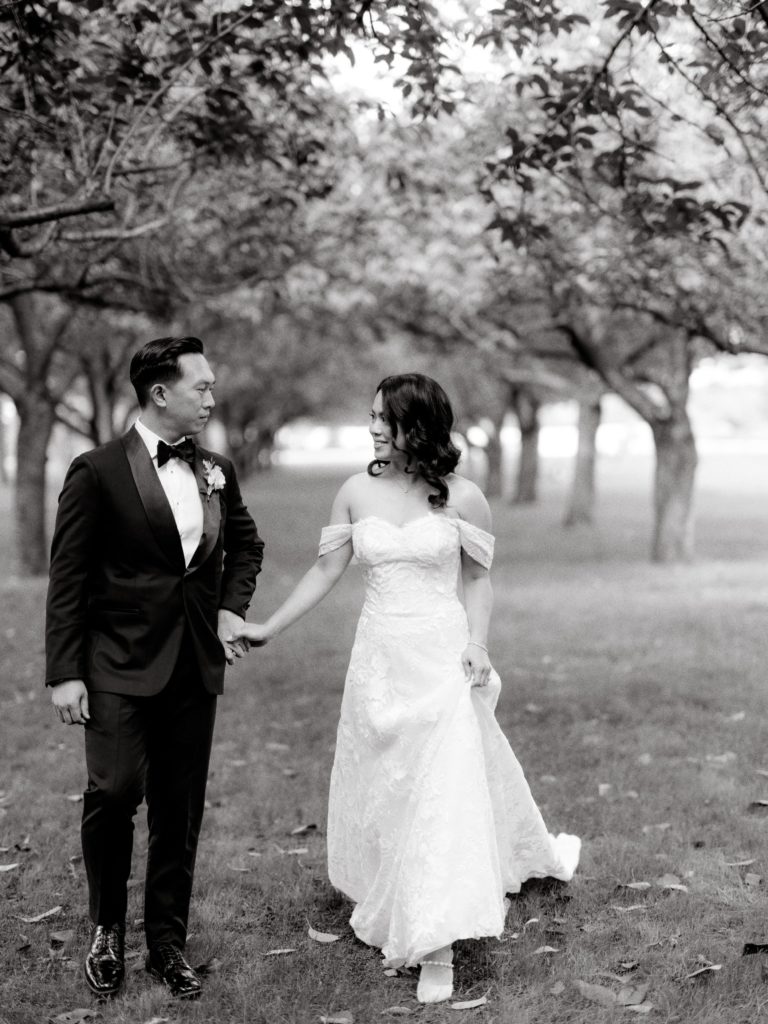 Black and white editorial image of the bride and the groom looking at each other's eyes in the middle of a garden. Image by Jenny Fu Studio