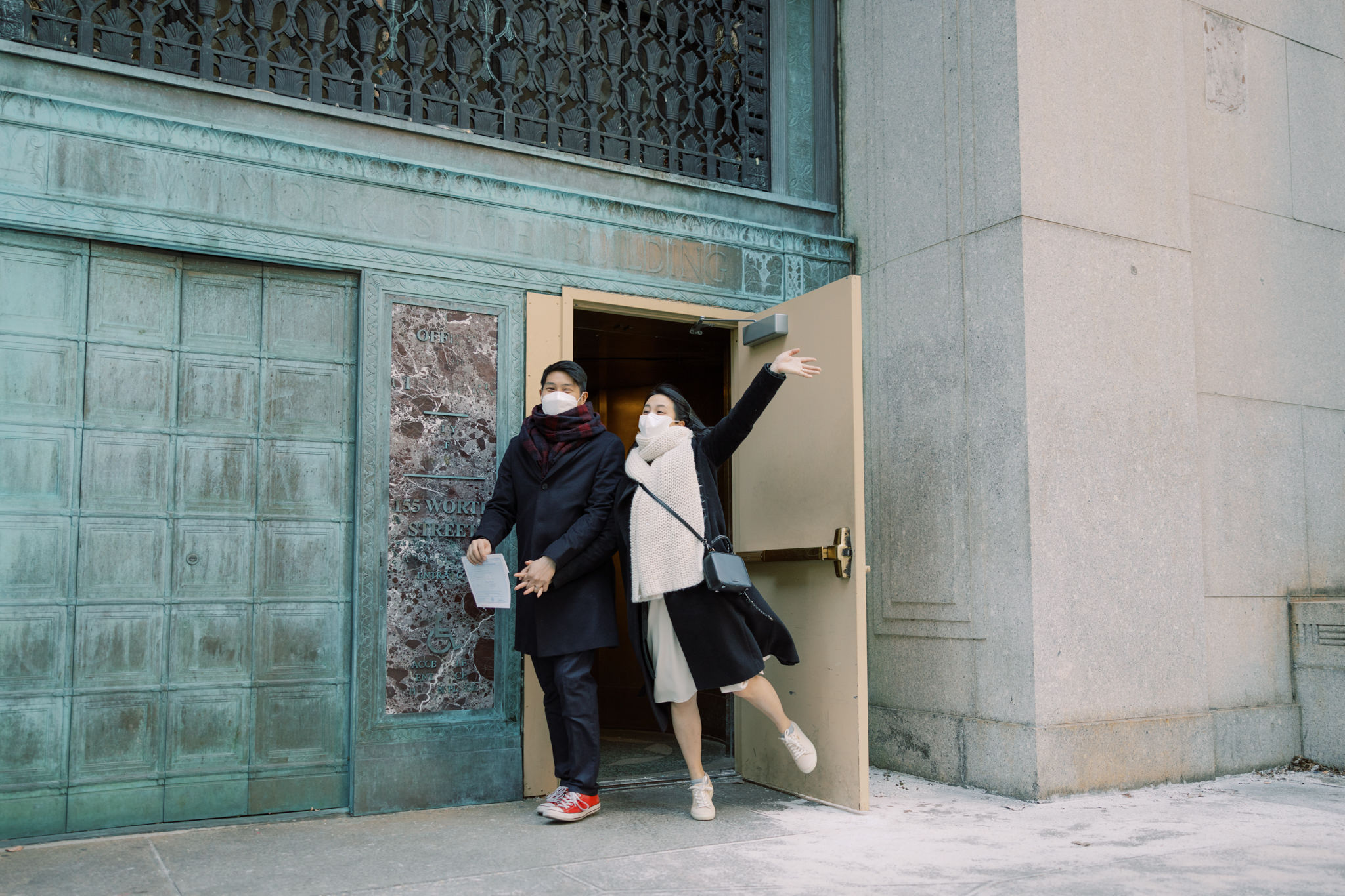 The bride and groom are happily going out of the exit door. 2022 city hall wedding in NYC photo by Jenny Fu Studio
